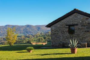 a stone house on a field with mountains in the background at Antica Corte Casa Marini in Polinago