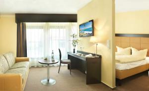 ein Hotelzimmer mit einem Bett und einem Schreibtisch in der Unterkunft Hotel zur Heideblüte in Hambühren