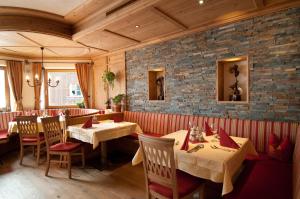 a restaurant with tables and chairs and a brick wall at Gasthof Alpenblick in Tobadill