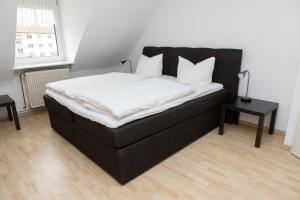 ein schwarzes Bett mit weißer Bettwäsche und Kissen in einem Zimmer in der Unterkunft Zwehrener Hof in Kassel