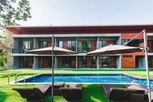 a house with a swimming pool and two umbrellas at Stucco Loft Residency in Chiang Mai