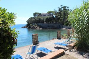 un gruppo di sedie su una spiaggia accanto all'acqua di Residence Villa La Pineta a Cavo