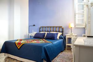 a bedroom with a blue bed with blue sheets at Villa Alicia Guest House in Málaga