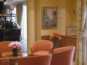 a dining room with a table and chairs and a vase of flowers at Hôtel La Flore in Villefranche-sur-Mer