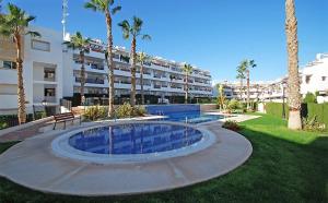 a swimming pool in front of a building with palm trees at Linnea Sol Blanca in Villamartin