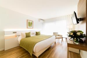 a hotel room with a bed and a television at Hôtel Hélios in Juan-les-Pins