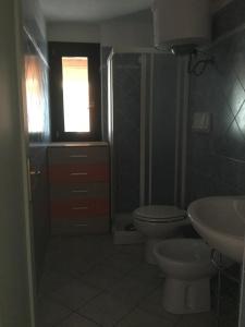 Un baño con inodoro, lavabo y ventana. en Residence Valledoria 2, en Valledoria 10 fotos más
