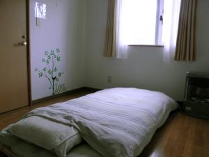 a bedroom with a bed in a room with a window at Guest House Annabel in Hakodate