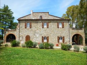 ein altes Steinhaus auf einem Grasfeld in der Unterkunft Colle Cavalieri - Country House in Gavorrano