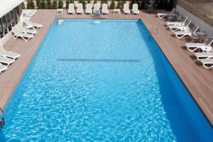 a large swimming pool with lounge chairs in a hotel at Hotel Castilla Alicante in Alicante