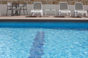 a group of chairs sitting next to a swimming pool at Hotel Castilla Alicante in Alicante