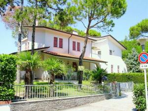 une maison blanche avec une clôture devant elle dans l'établissement Lignano Riviera with fireplace & air conditioning, à Lignano Sabbiadoro