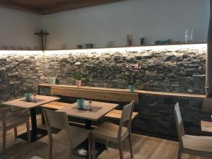 ein Restaurant mit 2 Tischen und Stühlen und einer Steinmauer in der Unterkunft Seehotel Lilly in Strobl