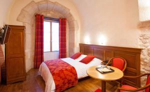 1 dormitorio con cama, mesa y ventana en Logis Hôtel Le Cheval Blanc, en Langres