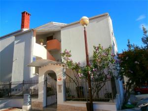 ein weißes Haus mit einem Tor und einem Straßenlicht in der Unterkunft Apartments Song in Split