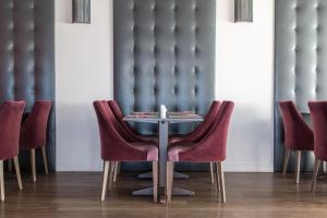 a dining room with a table and red chairs at Saint Aubin Logis Hôtel & Restaurant in Saint-Aubin-sur-Mer