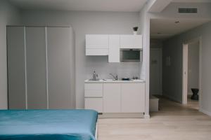 トラーニにあるTrani Rent Roomsの白いキッチン(ベッド1台、シンク付)