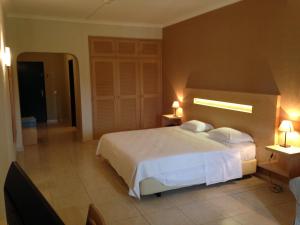 a bedroom with a white bed and two night stands at Vilamar in Luz