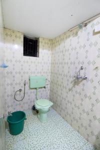 a bathroom with a green toilet and a bucket at Brittos Homestay in Mandrem