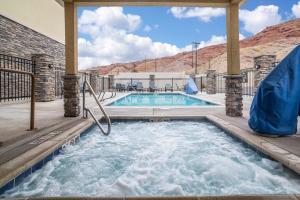 a jacuzzi tub in a patio next to a swimming pool at Comfort Suites Moab near Arches National Park in Moab