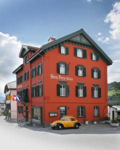 a yellow car parked in front of a red building at Posta Veglia in Laax
