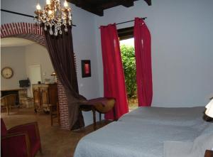 フィジャックにあるLe Clos Saint Paulのベッドルーム1室(赤いカーテンと椅子付きのベッド1台付)