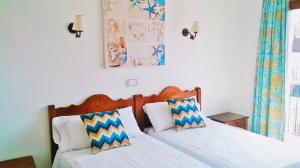 a bedroom with two beds with blue and white pillows at Hostal Rey in Santa Eularia des Riu