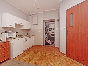 a kitchen with white cabinets and a painting of a woman at Apartament Kameralny na Starówce in Gdańsk