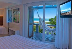 a bedroom with a bed and a balcony with the ocean at Pousada Morada dos Sisais in Praia do Rosa