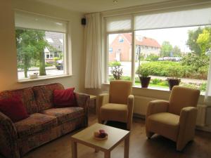 een woonkamer met een bank, 2 stoelen en een raam bij Tranquil holiday home in West Gradijk in West-Graftdijk