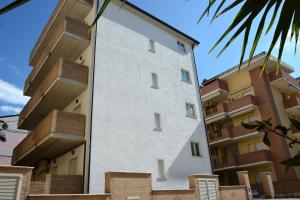 - un bâtiment blanc à côté de certains immeubles d'appartements dans l'établissement Stella Marina, à Alba Adriatica