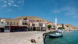 a small boat in the water next to a group of buildings at Spitakia in Halki