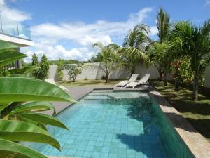 a swimming pool with two chairs and palm trees at Villa Soleil in Trou aux Biches