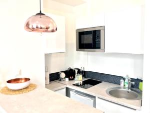 uma cozinha branca com um lavatório e um micro-ondas em MIDPOINT STUDİOS by Life Renaissance em Estrasburgo