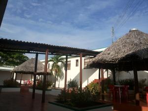 un edificio con dos sombrillas de paja, mesas y sillas en Hotel Orinoco Real, en Puerto Inírida