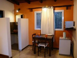 a small kitchen with a table and a small refrigerator at La Catalina Suites de Campo in Nono