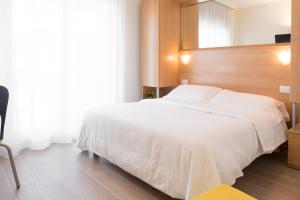 a bedroom with a large white bed with a wooden headboard at Hotel Mediterraneo in Sottomarina