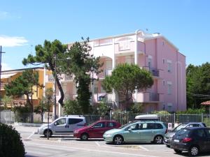 コマッキオにあるBelvilla by OYO Lido Estensi Trilo Doriaのピンクの建物の前に車を停めた駐車場