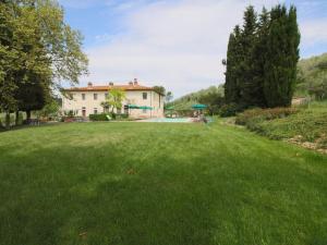 un ampio cortile erboso con una casa sullo sfondo di Lavish Farmhouse in San Gimignano with Swimming Pool a San Gimignano