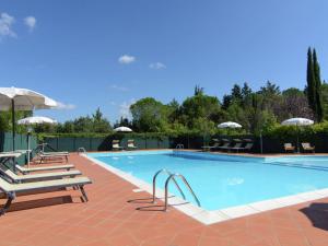 Chiassa SuperioreにあるSpacious farmhouse with poolのラウンジチェアとパラソル付きのスイミングプール