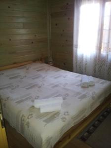 a bed in a wooden room with a window at Zlatnoto Pile Restaurant & Rooms in Kranevo