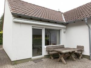 uma casa branca com um banco e uma janela em Absolute holiday house at the edge of the forest em Leideneck