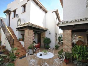 a patio with white chairs and a table in front of a house at Belvilla by OYO Cortijo las Monjas in Periana
