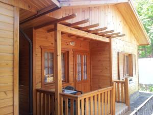 eine Holzhütte mit einer Veranda und einer Terrasse in der Unterkunft Zlatnoto Pile Restaurant & Rooms in Kranewo