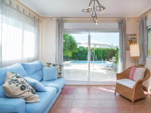 salon z niebieską kanapą i przesuwanymi szklanymi drzwiami w obiekcie Belvilla by OYO Villa Mosa Claire w mieście Baños y Mendigo
