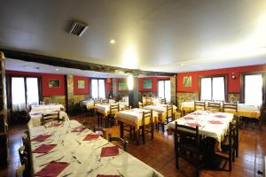 a dining room with tables and chairs and red walls at Hotel Rural Bereau in Lesaka