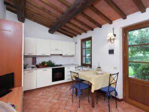 ピストイアにあるTraditional Farmhouse near Pistoia with Gardenの白いキャビネット、テーブルと椅子付きのキッチンが備わります。