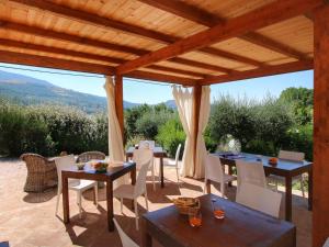 een patio met tafels en stoelen onder een houten pergola bij Belvilla by OYO Ginestrilo in Assisi