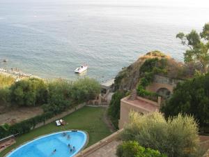 une grande piscine avec un bateau à côté de l'océan dans l'établissement Belvilla by OYO Mandorlo, à Ricadi