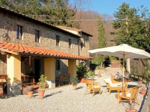 une terrasse avec une table et un parasol en face d'un bâtiment dans l'établissement Belvilla by OYO Olivi Rosso, à San Quirico